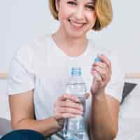 Foto gratuita mujer sonriente con la botella de agua abierta