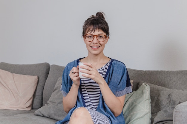 Foto gratuita mujer sonriente con café en el sofá