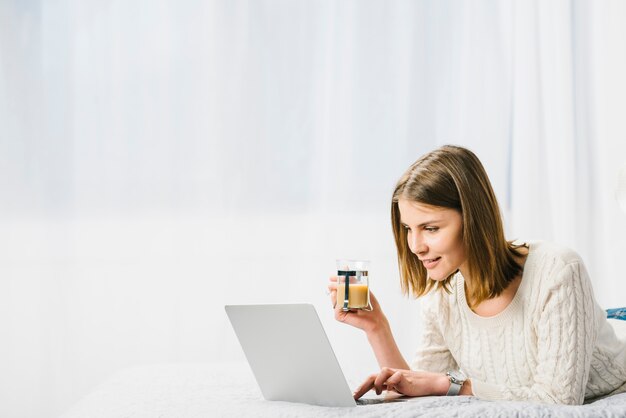 Mujer sonriente con café usando la computadora portátil