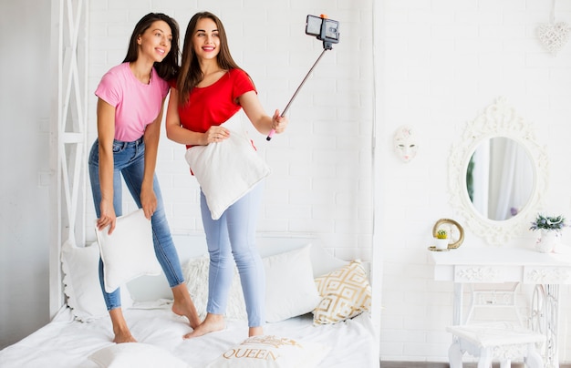 Mujer sonriente en la cama con almohada tomando foto