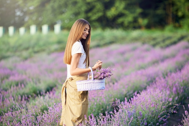 Mujer sonriente caminando con canasta campo lavanda