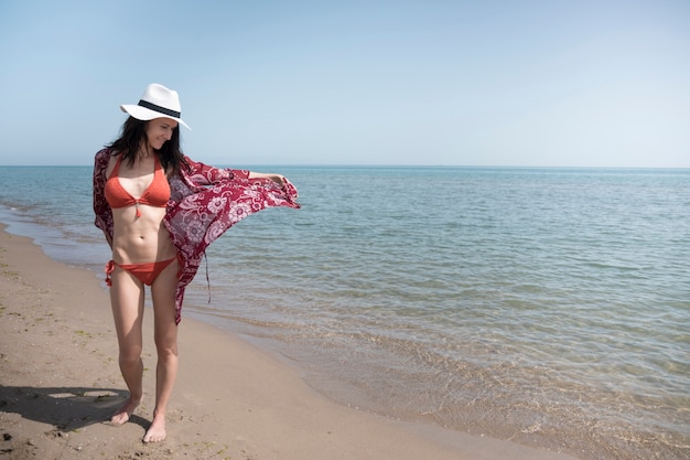 Mujer sonriente caminando a la orilla del mar