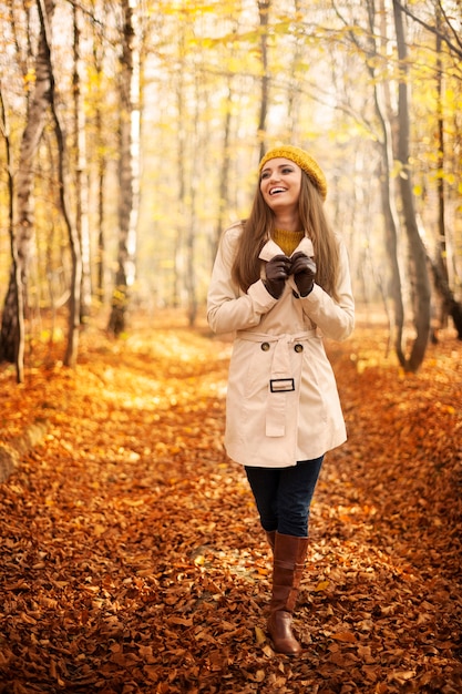 Mujer sonriente caminando en el parque en la temporada de otoño