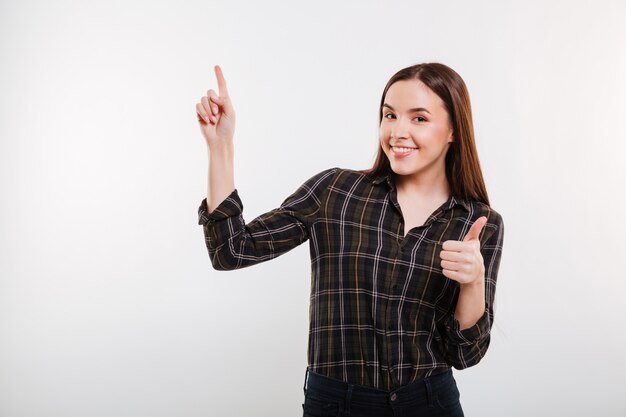 Mujer sonriente en camisa apuntando hacia arriba