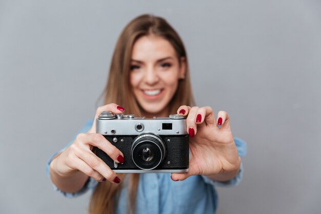 Mujer sonriente en camisa haciendo teléfono en cámara retro