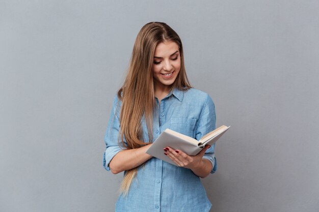 Mujer sonriente en camisa leyendo libro