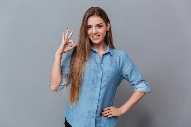 Mujer sonriente en camisa mostrando signo ok