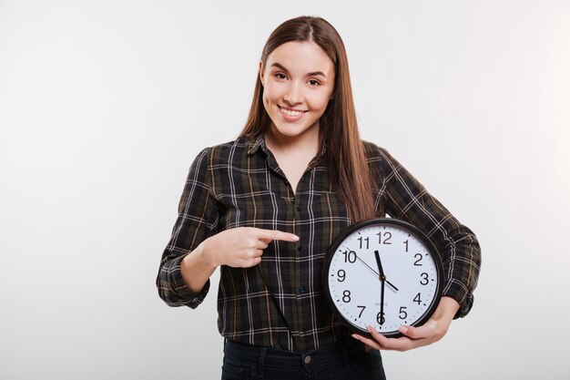 Mujer sonriente en camisa sosteniendo el reloj