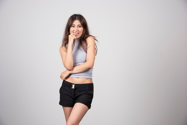 Una mujer sonriente en camiseta gris de pie y posando.