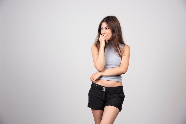 Una mujer sonriente en camiseta gris de pie y posando.