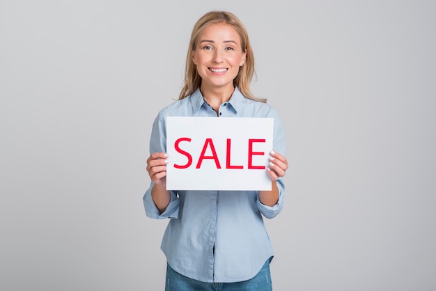 Mujer sonriente con cartel de venta