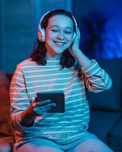 Mujer sonriente en casa con auriculares y tableta