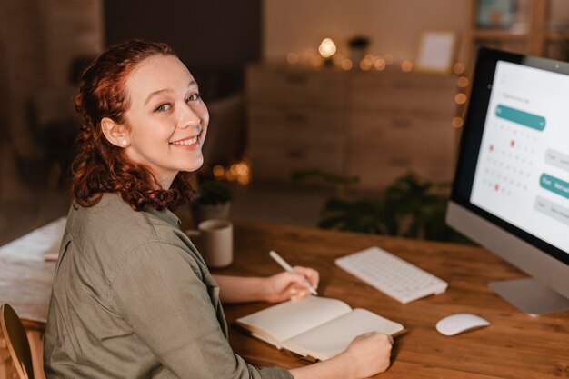 Mujer sonriente en casa usando su computadora