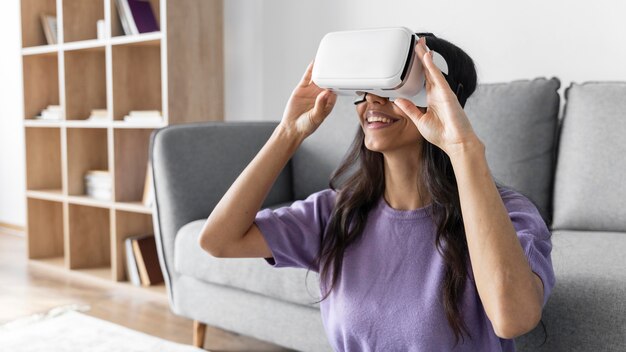 Mujer sonriente con casco de realidad virtual en casa