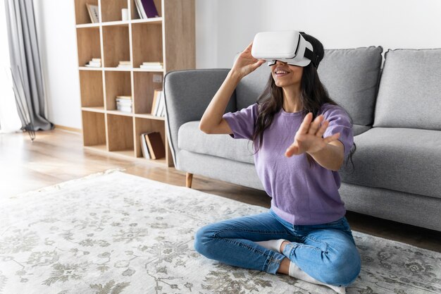 Mujer sonriente con casco de realidad virtual en casa