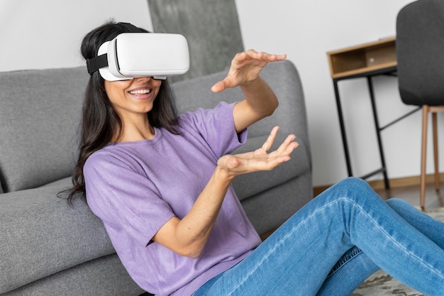 Foto gratuita mujer sonriente con casco de realidad virtual en casa