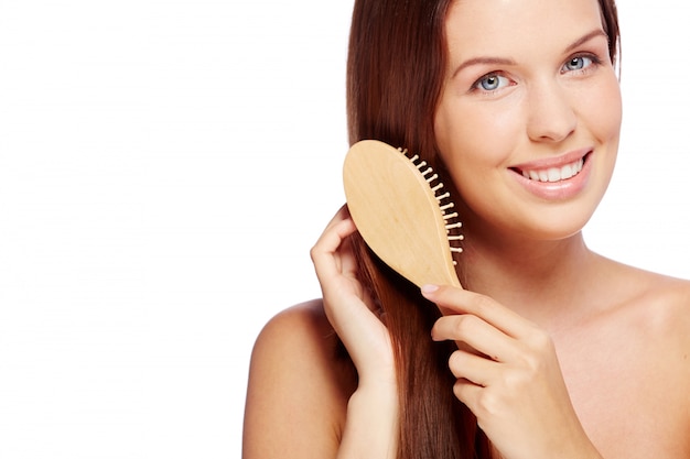 Mujer sonriente cepillándose su pelo sano