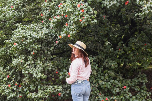 Mujer sonriente cerca de muchas flores que crecen en ramitas verdes