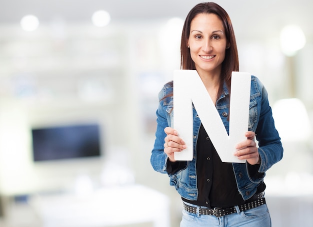 Mujer sonriente en chaqueta vaquera con la letra 