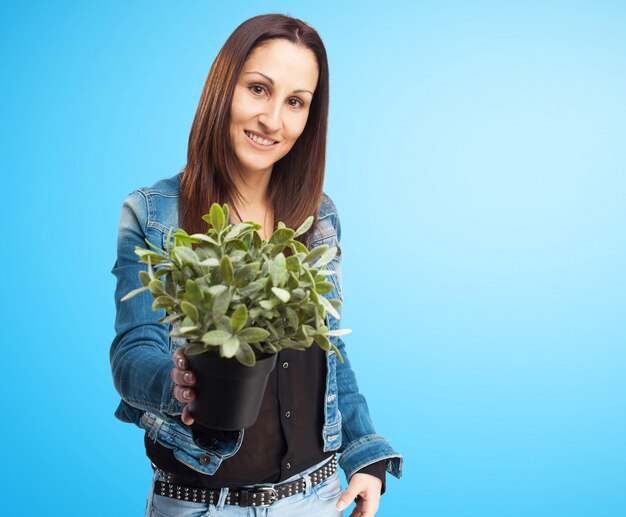 Foto gratuita mujer sonriente con chaqueta vaquera con una planta