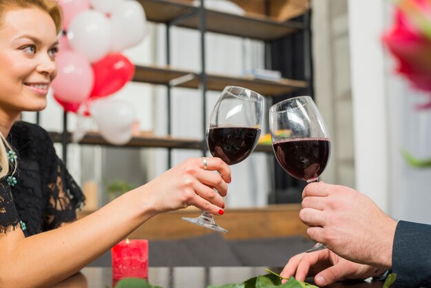 Mujer sonriente chocando copas de vino con el hombre en la mesa