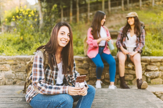 Mujer sonriente con chocolate cerca de amigos