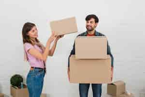 Foto gratuita mujer sonriente colocando la pila de cajas de cartón sobre la mano de su esposo