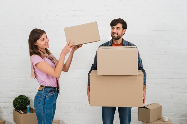 Mujer sonriente colocando la pila de cajas de cartón sobre la mano de su esposo