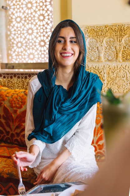 Mujer sonriente comiendo en restaurante arabe