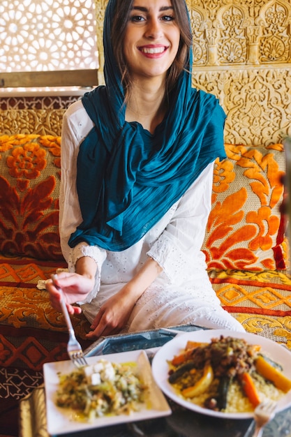 Mujer sonriente comiendo en restaurante arabe