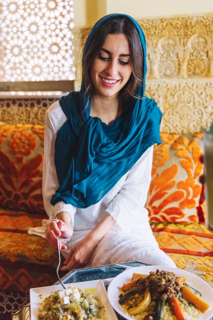 Mujer sonriente comiendo en restaurante arabe