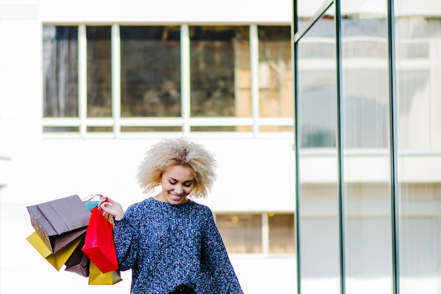 Mujer sonriente con compras en la calle de la ciudad