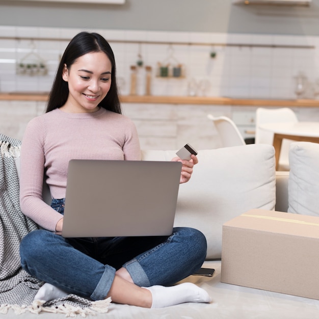 Mujer sonriente de compras en línea con laptop y tarjeta de crédito