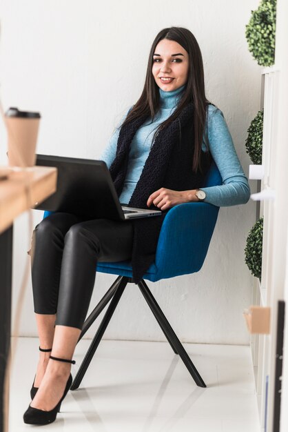 Mujer sonriente con la computadora portátil en la oficina