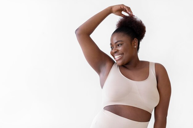 Mujer sonriente confiada que presenta mientras usa un moldeador del cuerpo con espacio de copia