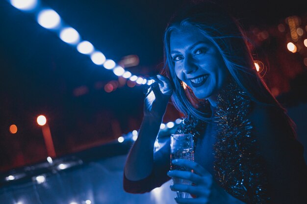 Mujer sonriente con una copa de champán y lámparas azules