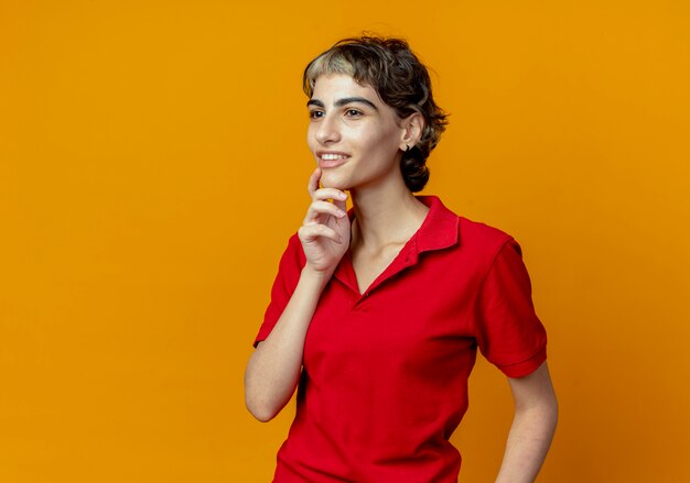 Mujer sonriente con corte de pelo pixie tocando la barbilla mirando directamente