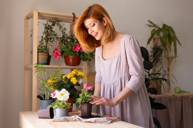 Mujer sonriente cuidando de plano medio de la planta