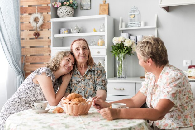 Mujer sonriente desayunando con su madre y su abuela en casa
