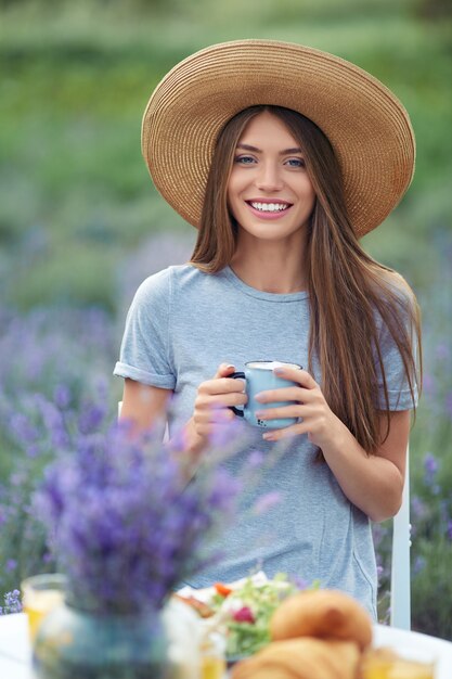 Mujer sonriente disfrutando de un café en el campo de lavanda