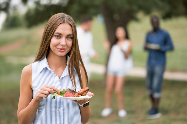 Mujer sonriente disfrutando de la comida en una barbacoa