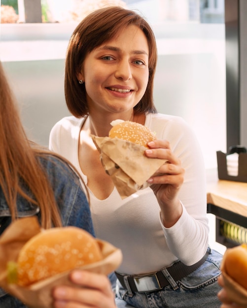 Mujer sonriente disfrutando de una hamburguesa