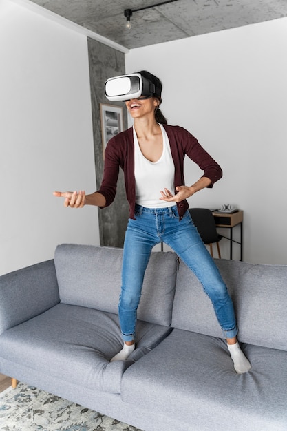 Mujer sonriente divirtiéndose en casa con casco de realidad virtual