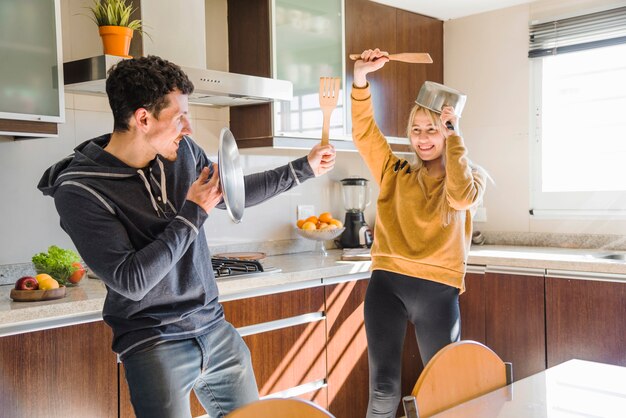 Mujer sonriente divirtiéndose con su marido en la cocina