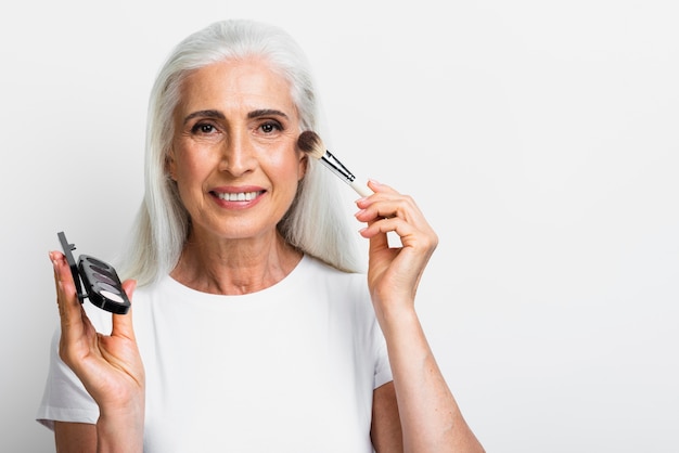 Mujer sonriente con elementos de maquillaje