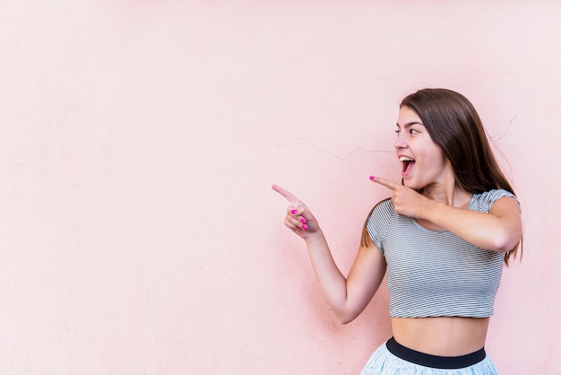 Foto gratuita mujer sonriente emocionada que señala por los dedos