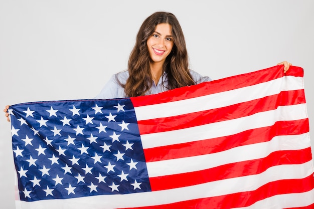 Mujer sonriente con enorme bandera de Estados Unidos