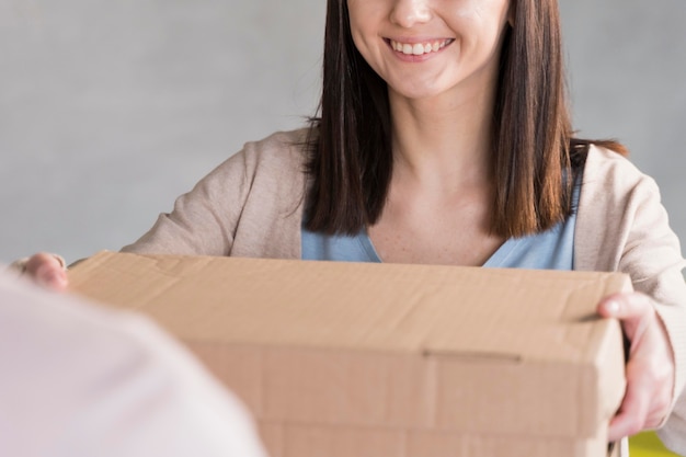 Mujer sonriente entrega caja de cartón
