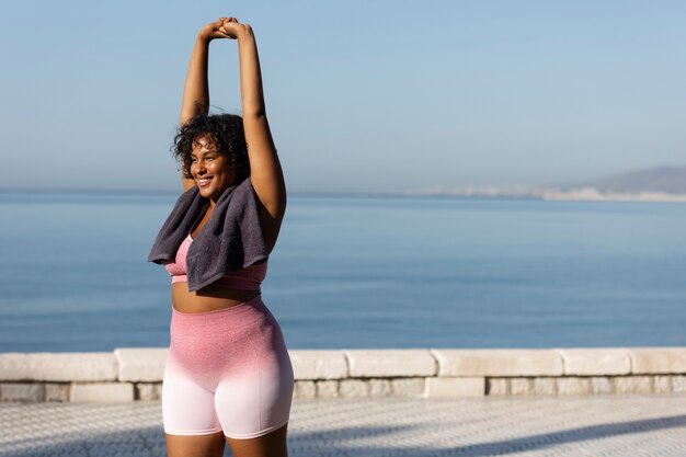 Mujer sonriente entrenando al aire libre tiro medio