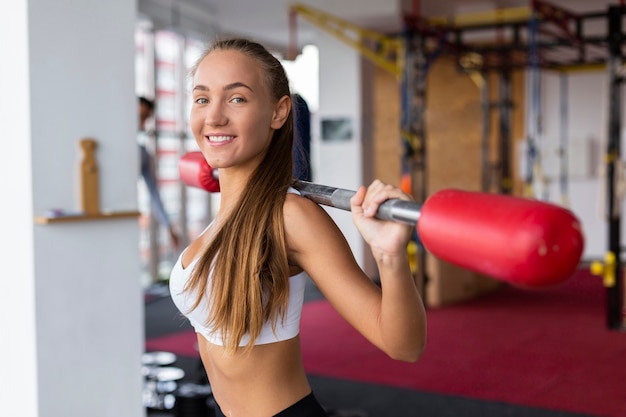 Mujer sonriente entrenando con barra de pesas